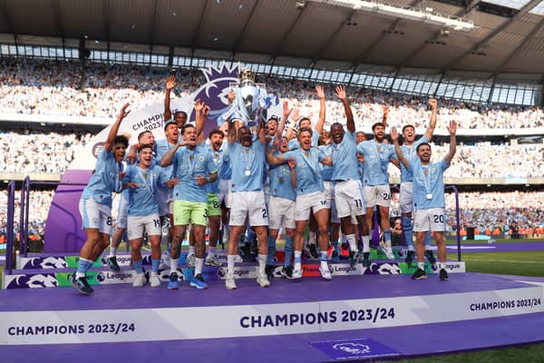 Manchester City's players lift the trophy on the pitch.
