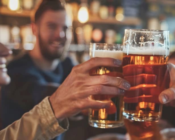 Friends drinking pints and toasting beer at a pub. Image: Sasint/stock.adobe