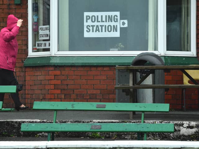 A woman covers her head in heavy rain as she enters a polling station 
