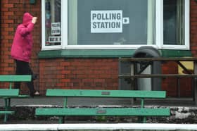 A woman covers her head in heavy rain as she enters a polling station 