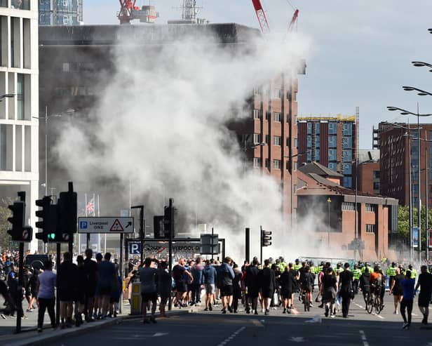 Smoke billows as police officers face off protesters in Liverpool on August 3, 2024 during the 'Enough is Enough' demonstration held in reaction to the fatal stabbings in Southport on July 29.