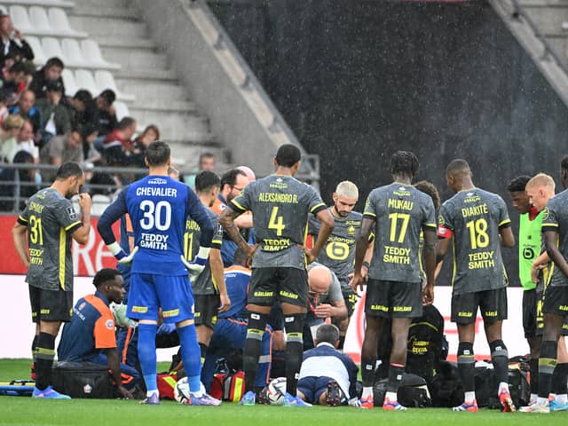 Lille's players stand next to Angel Gomes as he receives medical attention.