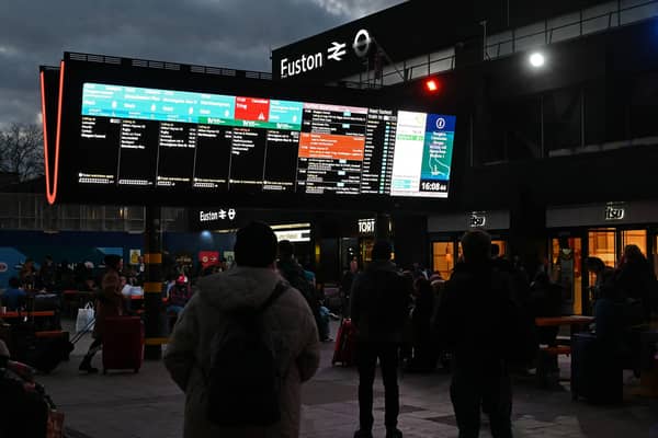 Rail travellers look at an electronic information board displaying train time information outside Euston Station in London. Photo: JUSTIN TALLIS/AFP via Getty Images