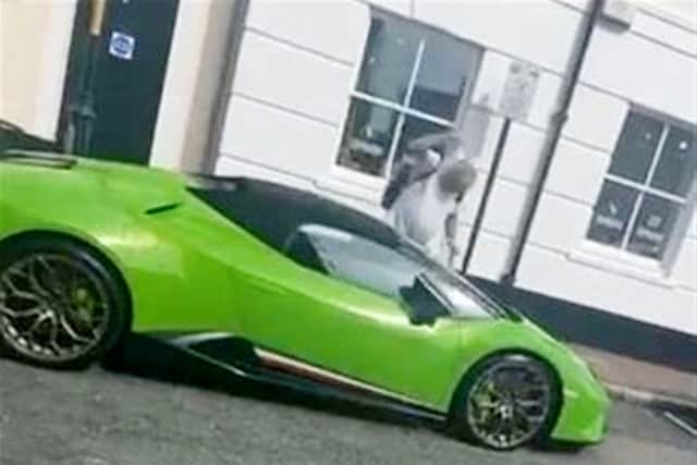 Darren Babbage raises an empty pint glass to smash down on Mat Velvick's Lamborghini.
