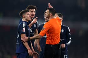Referee Andrew Madley gestures towards Manuel Ugarte and Harry Maguire of Manchester United during the Emirates FA Cup Third Round match between Arsenal and Manchester United at Emirates Stadium on January 12, 2025 in London, England.