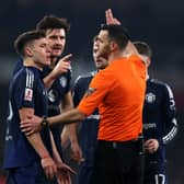 Referee Andrew Madley gestures towards Manuel Ugarte and Harry Maguire of Manchester United during the Emirates FA Cup Third Round match between Arsenal and Manchester United at Emirates Stadium on January 12, 2025 in London, England.