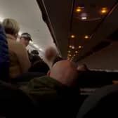 Security removing the disruptive woman from the flight. A woman who went on a foul mouthed racist tirade while on a flight to Manchester was arrested and taken into custody.