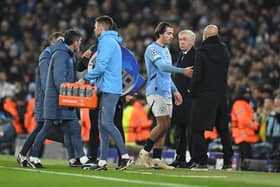 Pep Guardiola, Manager of Manchester City, speaks to Jack Grealish of Manchester City as he leaves the pitch after picking up an injury during the UEFA Champions League 2024/25 League Knockout Play-off first leg match between Manchester City and Real Madrid C.F. at Manchester City Stadium on February 11, 2025 in Manchester, England. 