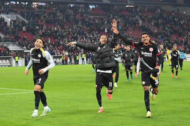 Frankfurt's Egyptian forward #07 Omar Marmoush (L), Frankfurt's French forward #11 Hugo Ekitike (C) and Frankfurt's German forward #36 Ansgar Knauff (R) celebrate with the fans after winning the German first division Bundesliga football match VfB Stuttgart vs Eintracht Frankfurt. (Photo by THOMAS KIENZLE/AFP via Getty Images)