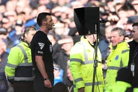 Match Referee, Andrew Madley is pictured consulting the Video Assistant Referee (VAR) to determine a penalty during the Premier League match between Everton FC and Manchester United FC at Goodison Park on February 22, 2025 in Liverpool, England