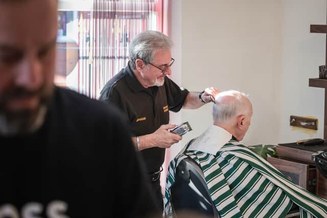 Graham Evans cutting the hair of his regular customer John