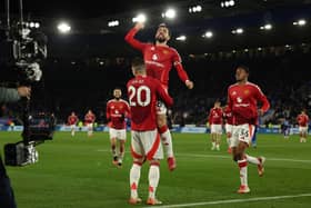 Manchester United's Portuguese midfielder #08 Bruno Fernandes leaps into the arms of Manchester United's Portuguese defender #20 Diogo Dalot as he celebrates scoring their third goal during the English Premier League football match between Leicester City and Manchester United at King Power Stadium in Leicester, central England on March 16, 2025.