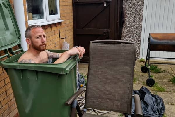 Martin Lynch taking a cold water bath in his wheelie bin