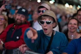 A fan in a bucket hat waits for Oasis to take to the stage at the Principality Stadium, Cardiff, as the band's long-awaited reunion tour kicks off in Wales. 			