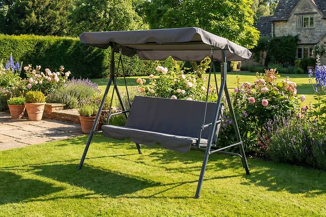 The grey three-seater garden swing chair includes padded cushions and an adjustable canopy for outdoor seating