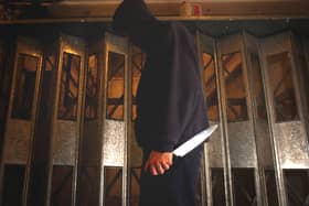 PICTURE POSED BY MODEL. A general view of a man in a hoodie holding a knife.