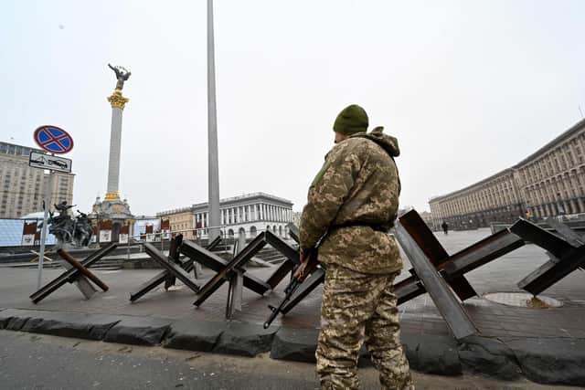 A fighter of the Ukrainian Territorial Defence Forces, the military reserve of the Ukrainian Armed Forces, stands guard at anti-tank constractions on the position at Independence Square in Kyiv on March 2, 2022