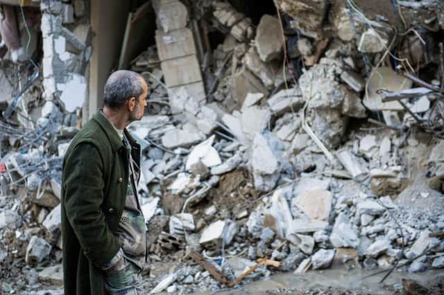 A man walks past a collapsed building in the town of Jbaleh in Syria's northwestern province of Latakia following the earthquake.