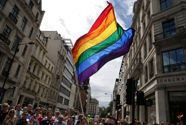 A rainbow flag is held aloft as the Pride in London parade makes its way through the streets of central, London.