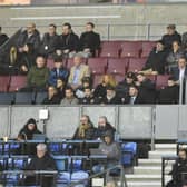 Wayne Rooney (centre of picture, wearing cap) was an interested spectator in the DW Stadium directors box on Monday night