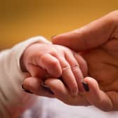 A mother holds the hand of a new baby.