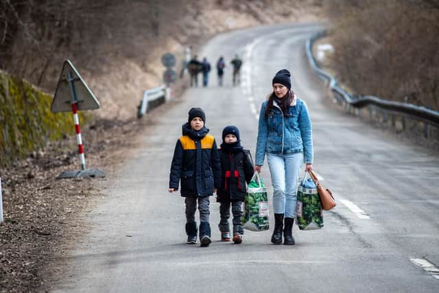 A woman with two children and carrying bags walk on a street to leave Ukraine after crossing the Slovak-Ukrainian border in Ubla, eastern Slovakia. Photo by PETER LAZAR/AFP via Getty Images