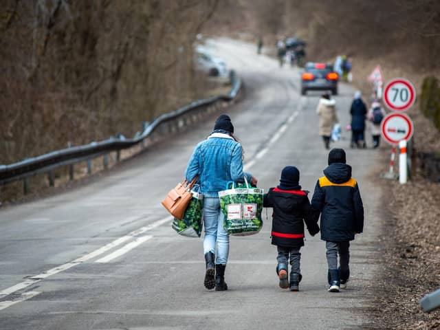 A woman with two children and carrying bags walk on a street to leave Ukraine, following Russia's invasion. Photo by Peter Lazar/AFP via Getty Images