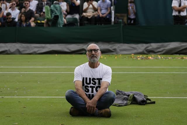 A Just Stop Oil protester sits on Court 18 on day three of the Wimbledon tennis championships in London, Wednesday, July 5, 2023. (AP Photo/Alastair Grant)