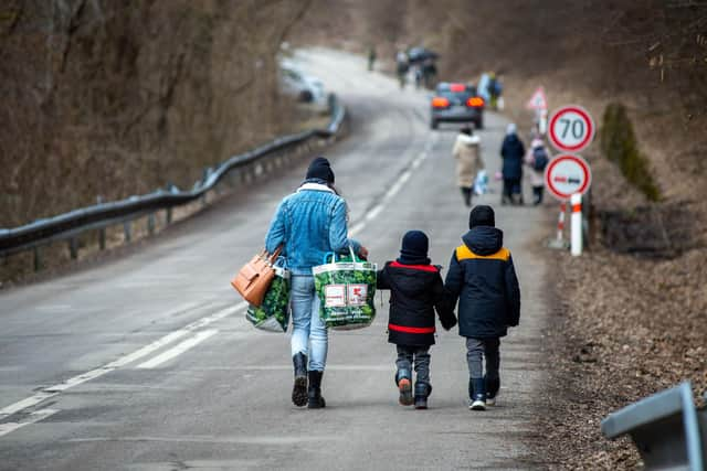 A woman with two children and carrying bags walk on a street to leave Ukraine after crossing the Slovak-Ukrainian border in Ubla, eastern Slovakia, close to the Ukrainian city of Welykyj Beresnyj, following Russia's invasion of the Ukraine. Photo by PETER LAZAR/AFP via Getty Images